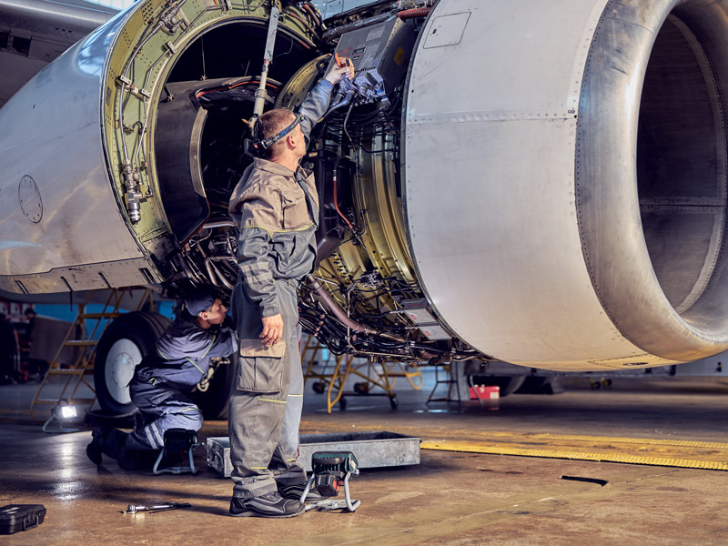 Aerospace industry specific ERP image showing factory worker assembling plane engine components