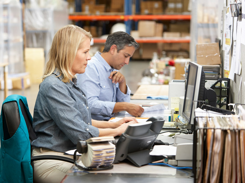 Finance workers on factory floor use computer with real-time integration to access up to date finance details