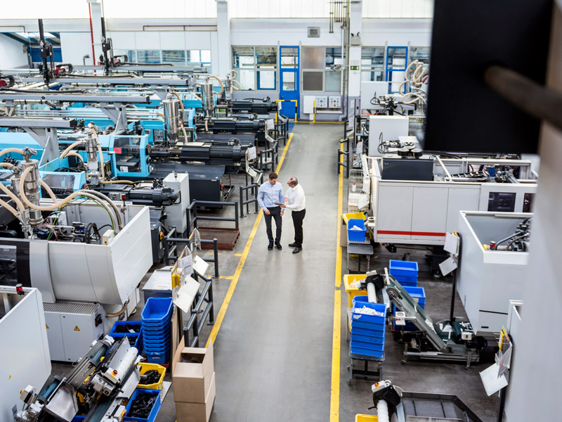 Two coworkers discuss real-time production data using tablet on the shop floor to understand the current manufacturing progress