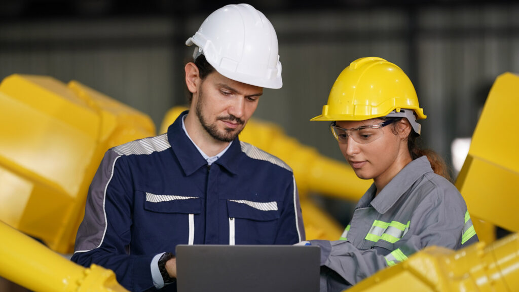 MRP System featured image showing two factory workers collaborating on a laptop to confirm Material requirements planning process