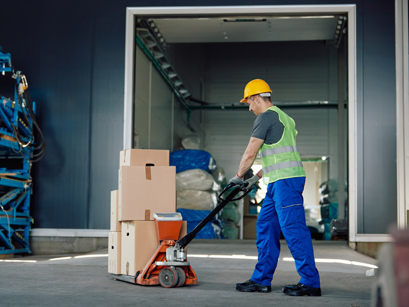 Warehouse worker loads boxes onto a vehicle using a trolley as part of the supply chain management process