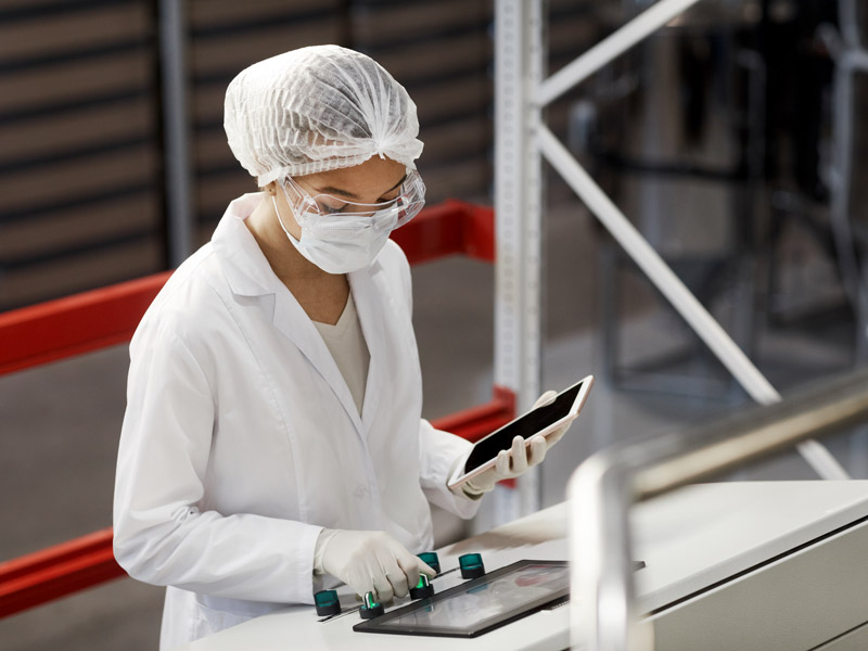 Female uses tablet to asset quality standards of medical device production line