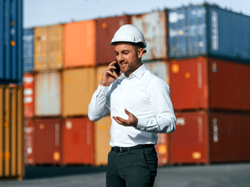 Logistics worker in shipping yard on phone is pleased with receiving direct updates via electronic data interchange EDI