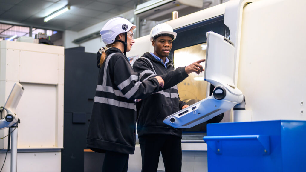 Plastic Components Inc Case Study Featured Image showing two factory workers discussing optimised manufacturing processes at machine