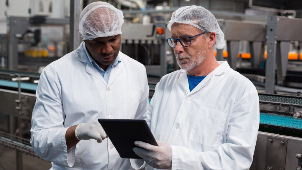 Factory coworkers review quality control of manufacturing operations using a tablet