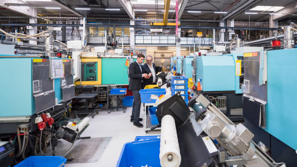 Trend Technologies Case Study Featured Image shows two workers discussing injection moulding on shop floor